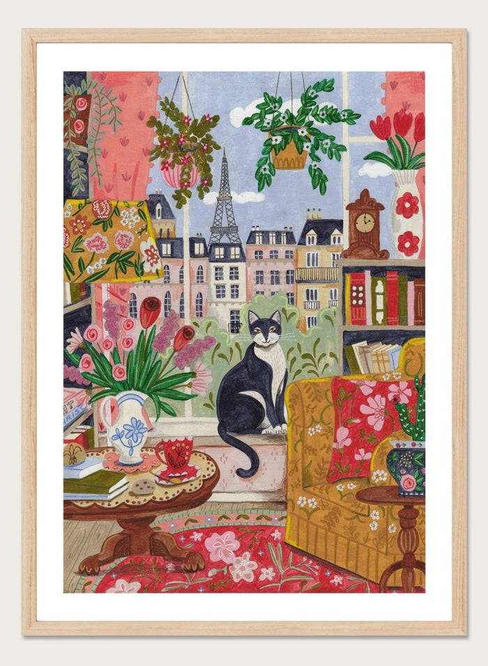 Colorful illustration of a living room with a cat, flowers, and a cityscape. Cozy Parisian Window Cat by Caroline Bonne Müller is a fine art print and wall poster of a cat by a window with Paris view and colorful interior.
