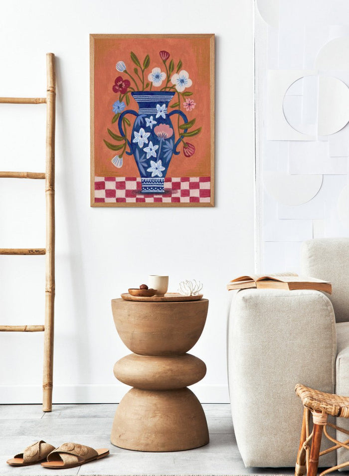 Decorative painting of a blue vase with floral patterns on a checkered floor against an orange wall. Folk Art Flower Vase by Caroline Bonne Müller is a fine art print and wall poster featuring a blue floral vase with colorful flowers on a checkered table.