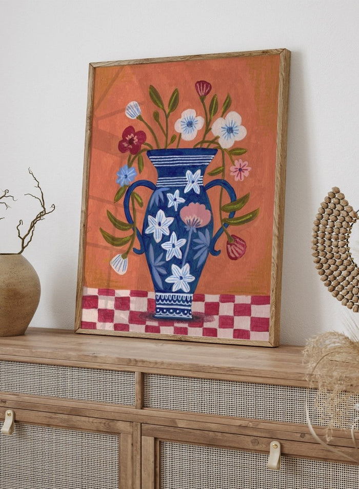 Decorative painting of a blue vase with floral patterns on a checkered floor against an orange wall. Folk Art Flower Vase by Caroline Bonne Müller is a fine art print and wall poster featuring a blue floral vase with colorful flowers on a checkered table.