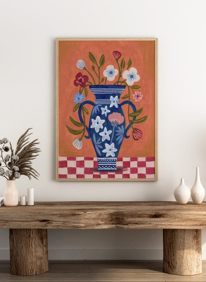 Decorative painting of a blue vase with floral patterns on a checkered floor against an orange wall. Folk Art Flower Vase by Caroline Bonne Müller is a fine art print and wall poster featuring a blue floral vase with colorful flowers on a checkered table.