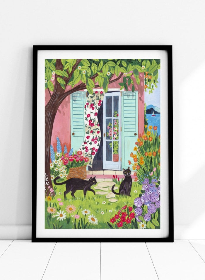 Garden Cats by the Sea by Caroline Bonne Müller is a colorful coastal garden art print featuring cats, florals, and seaside home in a modern aesthetic illustration style.