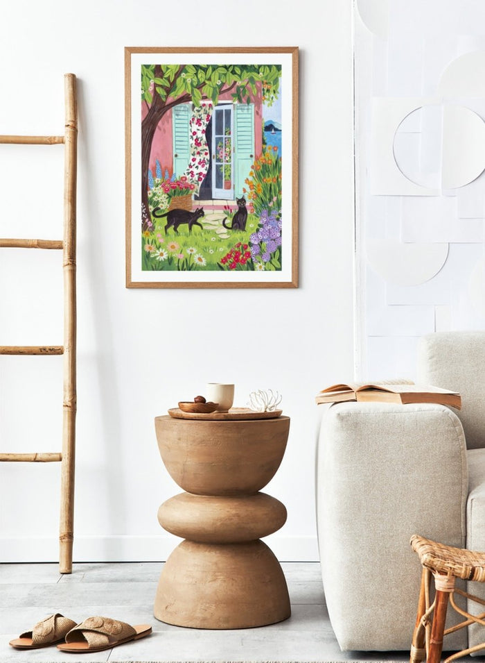 Garden Cats by the Sea by Caroline Bonne Müller is a colorful coastal garden art print featuring cats, florals, and seaside home in a modern aesthetic illustration style.