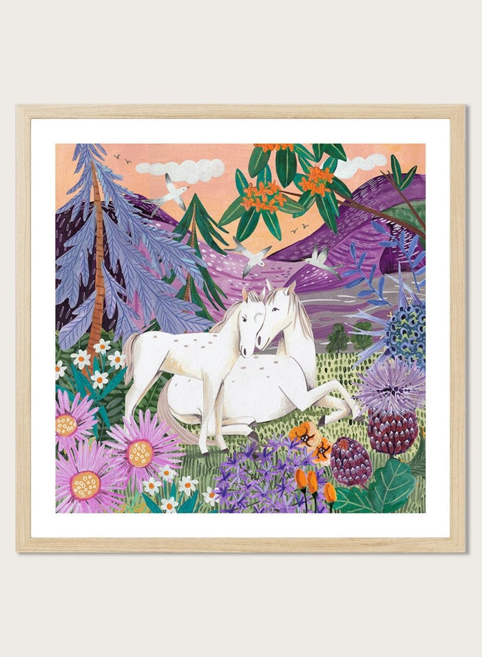 Framed artwork of two horses in a colorful forest scene with flowers and mountains. Horses in the Mountains by Caroline Bonne Müller is a fine art print and wall poster featuring two white horses surrounded by colorful flowers in a mountain landscape.