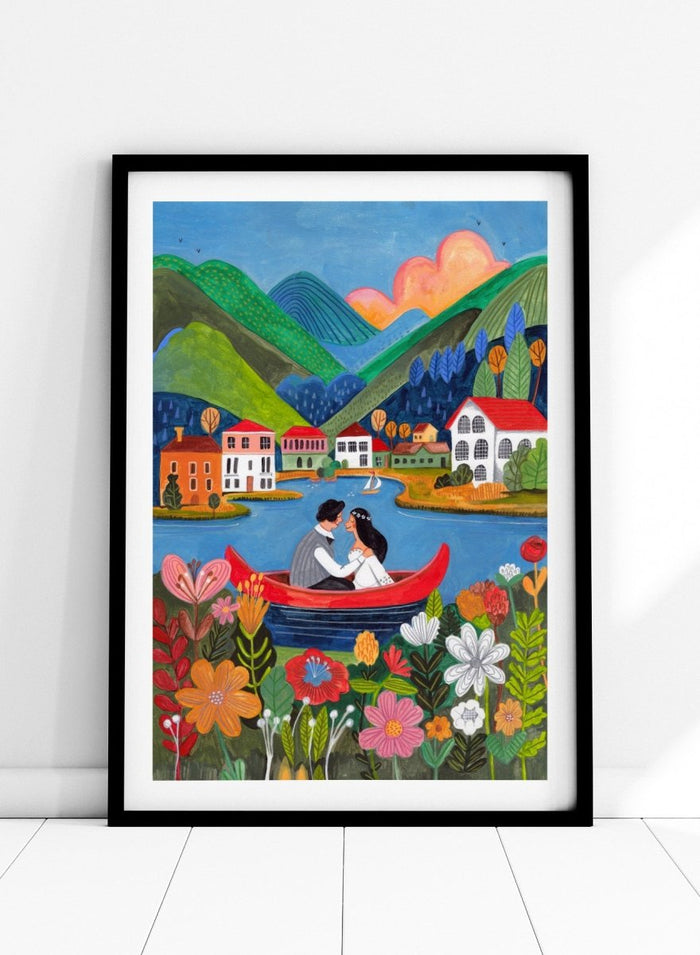 Couple in a red boat on a lake with mountains and houses in the background, surrounded by colorful flowers. Just Married Couple in a Boat by Caroline Bonne Müller is a romantic art print featuring couple illustration, lake scene, colorful flowers, and modern aesthetic wedding artwork.