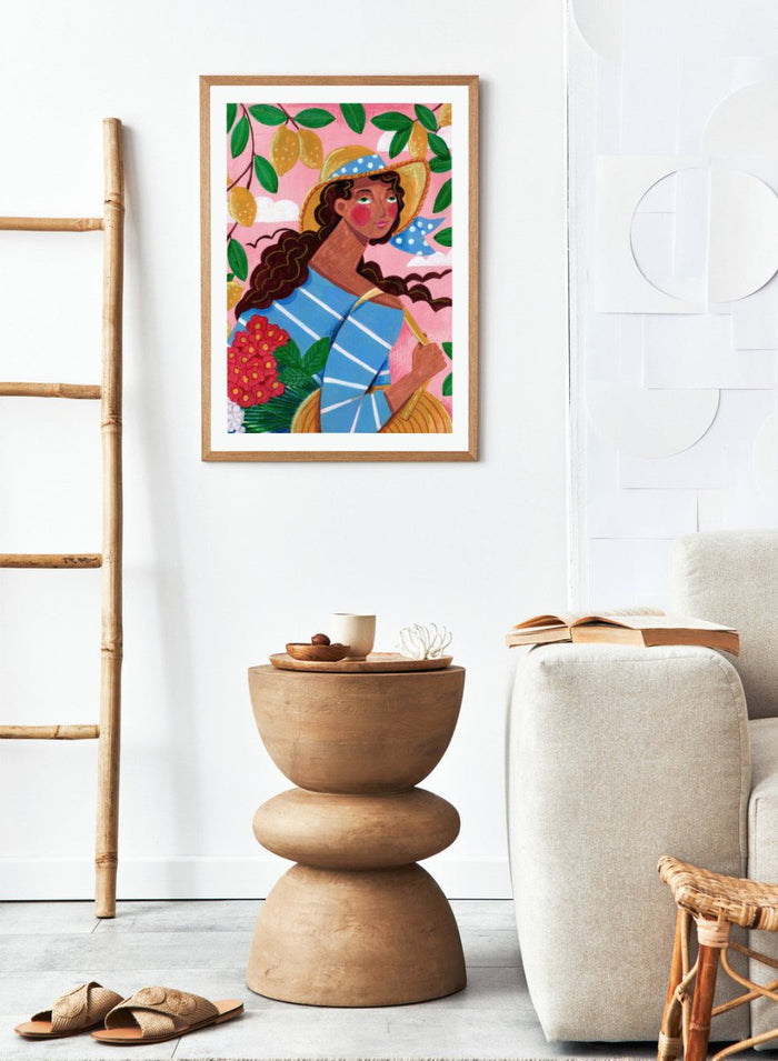 Colorful artwork of a woman with braided hair, wearing a straw hat and striped shirt, against a pink background with lemons and flowers. Lemon Tree Summer by Caroline Bonne Müller is a fine art print and wall poster of a woman under lemon branches with flowers in a bright modern aesthetic.