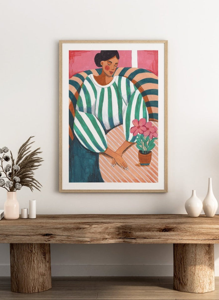 Artistic illustration of a person holding a potted plant with a colorful background. Peaceful Woman Home by Caroline Bonne Müller is a fine art print and wall poster of a woman seated indoors with flowers and striped patterns.