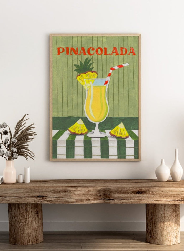 Illustration of a pina colada drink with pineapple slices on a checkered tablecloth. Piña Colada Summer Drink by Caroline Bonne Müller is a fine art print and wall poster of a pineapple cocktail with striped straw and green table setting.