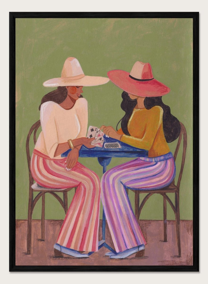 Two women playing cards at a table with colorful clothing and hats against a green background. Stylish Women Play Cards by Caroline Bonne Müller is a fine art print and wall poster featuring two fashionable women playing cards at a table.