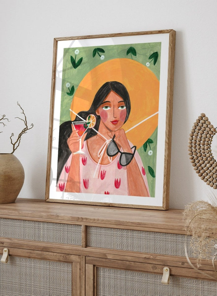 Illustration of a woman holding a cocktail and sunglasses with a sun and foliage background. Summer Woman Cocktail Hat by Caroline Bonne Müller is a fine art print and wall poster featuring a woman holding a cocktail with a bold yellow hat and bright summer colors.