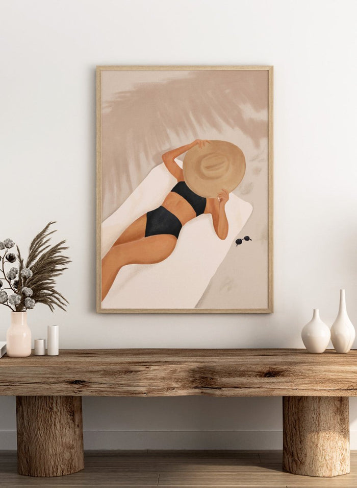 Woman in black bikini and straw hat lying on a towel with sunglasses nearby. Beach Day Relaxation by City Art is a modern beach art print featuring a woman in a black swimsuit, oversized sun hat, soft sand, and warm neutral tones.
