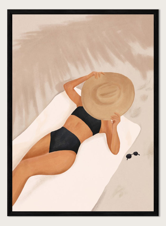 Woman in black bikini and straw hat lying on a towel with sunglasses nearby. Beach Day Relaxation by City Art is a modern beach art print featuring a woman in a black swimsuit, oversized sun hat, soft sand, and warm neutral tones.