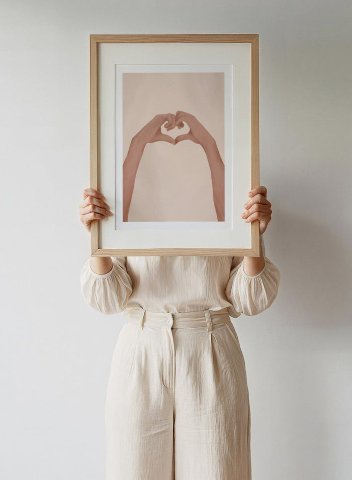Framed artwork of hands making a heart shape on a beige background. Heartfelt Hands by City Art is a modern figurative art print featuring hands forming a heart. A love-inspired wall poster from the It’s All Love collection.