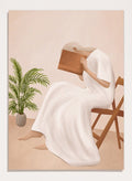 Person in a white dress holding a book, sitting on a chair with a plant nearby. Serene Woman Reading by City Art is a minimalist figurative art print featuring a woman reading in a flowing white dress with warm neutral tones and botanical details.