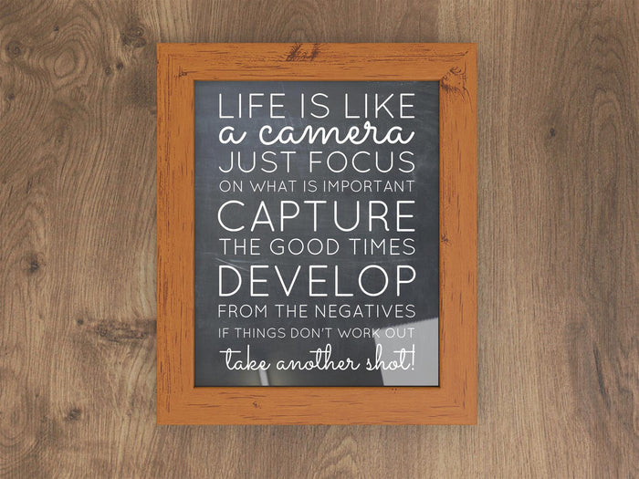 Dark teak picture frame with inspirational quote on a wooden background.