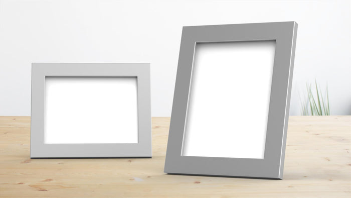 Two silver picture frames on a wooden surface, ideal for displaying photos and artwork in any room.