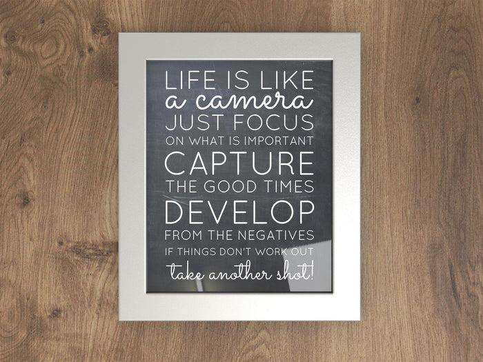 Inspirational quote framed in a silver picture frame accented by a wooden background.