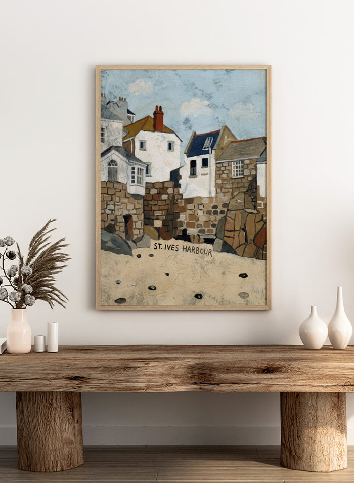A painted coastal scene labeled 'ST. IVES HARBOUR' showing white and stone buildings, rocky walls, sandy foreground, and a pale blue sky. Shop St. Ives Harbour Beach by Dan Hobday, a coastal wall art print featuring whitewashed houses, stone walls, sandy beach, and soft blue and earthy tones.