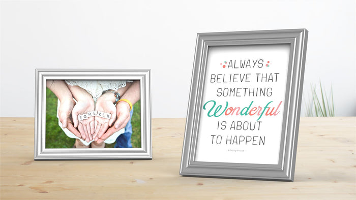 Two Devon Range silver picture and poster frames displaying a photo and inspirational quote on a wooden table.
