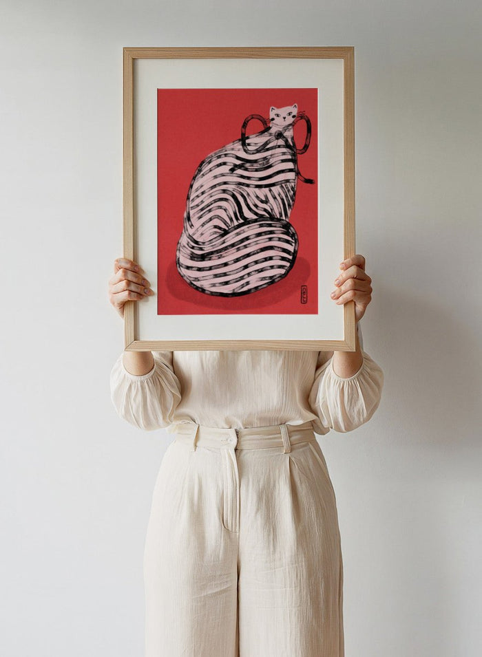 Illustration of a cat inside a ball of yarn on a red background. Black and White Striped Cat by Dirkie Nell is a playful cat art print featuring bold stripes and a red background. A colorful modern animal wall poster.