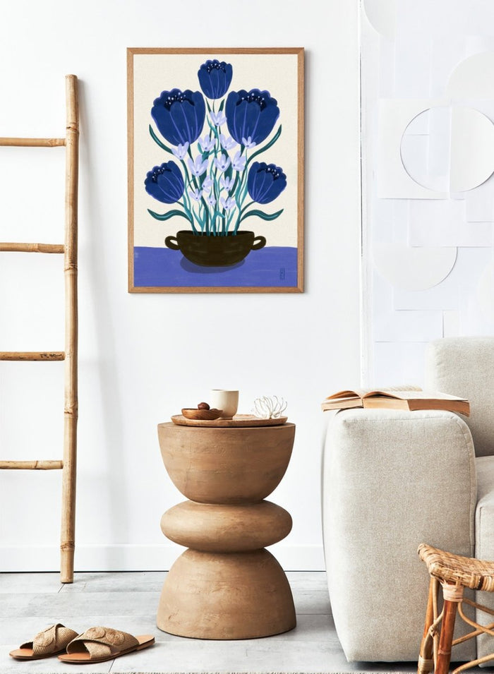 Artistic depiction of blue flowers in a black pot on a beige background. Blue Floral Arrangement by Dirkie Nell is a botanical floral art print featuring deep blue flowers, folk inspired illustration, modern wall art, and expressive hand painted details.
