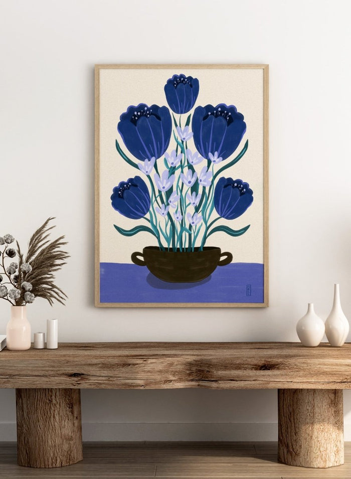 Artistic depiction of blue flowers in a black pot on a beige background. Blue Floral Arrangement by Dirkie Nell is a botanical floral art print featuring deep blue flowers, folk inspired illustration, modern wall art, and expressive hand painted details.