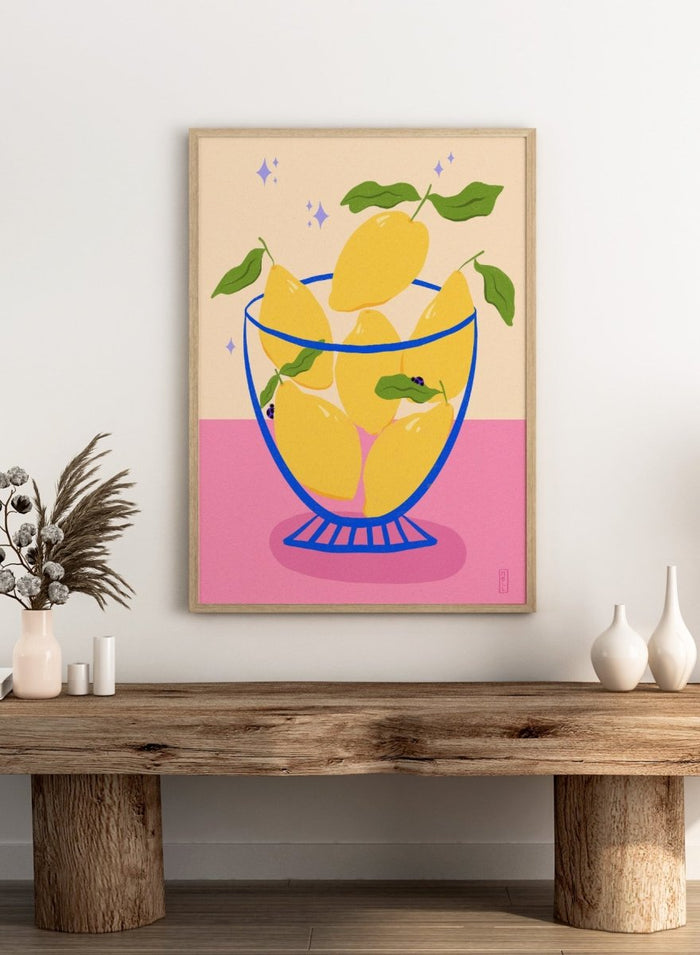Illustration of lemons in a glass bowl with green leaves on a pink and beige background. Blue Floral Arrangement by Dirkie Nell is a botanical floral art print featuring deep blue flowers, folk inspired illustration, modern wall art, and expressive hand painted details.