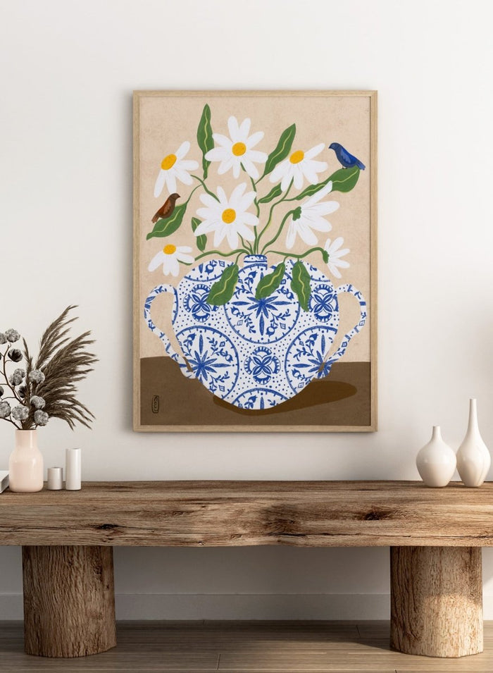 Decorative illustration of a blue and white teapot with daisies and birds on a beige background. Daisies In Blue Teapot by Dirkie Nell is a floral art print featuring white daisies, blue pottery, birds, and hand painted botanical details.