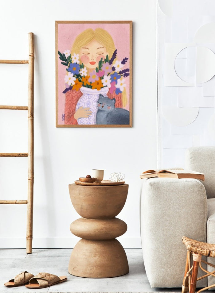 Illustration of a woman holding a vase of flowers and a cat on a pink background. Dreamy Girl Cat Flowers by Dirkie Nell is a colorful floral portrait art print featuring hand painted flowers, a sleepy cat, and soft contemporary illustration details.