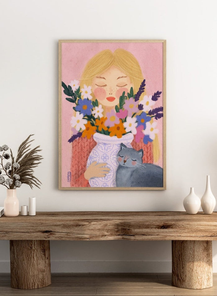 Illustration of a woman holding a vase of flowers and a cat on a pink background. Dreamy Girl Cat Flowers by Dirkie Nell is a colorful floral portrait art print featuring hand painted flowers, a sleepy cat, and soft contemporary illustration details.