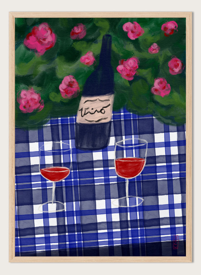A painted still life scene featuring a dark wine bottle labeled 'vino' on a blue-and-white plaid tablecloth, with two glasses of red wine and pink flowers against a green background. Shop Garden Wine Picnic by Dirkie Nell, a colorful still life art print featuring red wine, blue gingham, pink roses, and a warm summer garden mood.
