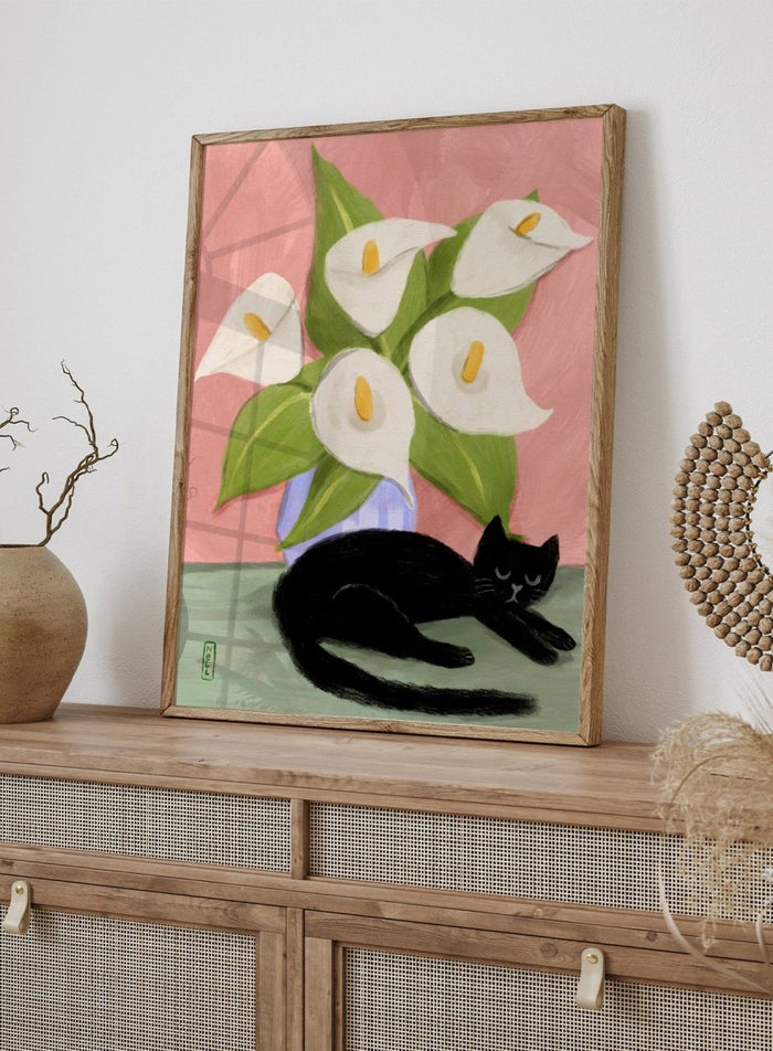 Black cat lying on a surface with white flowers in a blue vase against a pink background. Lilies In a Vase and a Black Cat by Dirkie Nell is a contemporary floral cat art print featuring hand painted lilies, soft pink tones, and playful still life illustration.