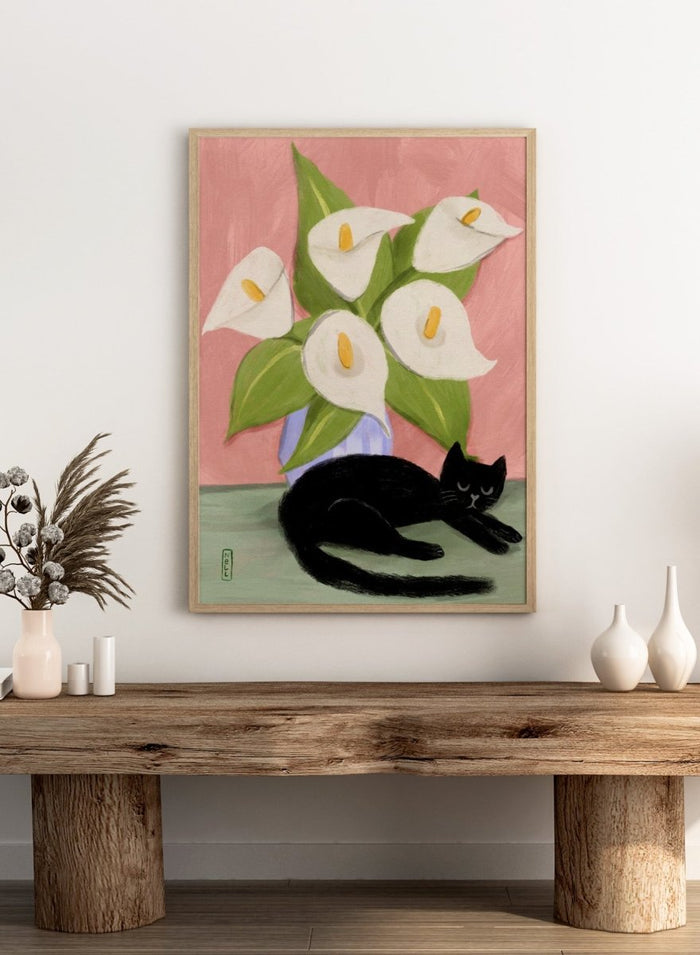 Black cat lying on a surface with white flowers in a blue vase against a pink background. Lilies In a Vase and a Black Cat by Dirkie Nell is a contemporary floral cat art print featuring hand painted lilies, soft pink tones, and playful still life illustration.