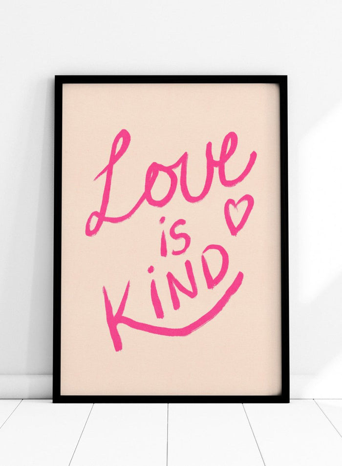Pink text 'Love is Kind' with a heart on a light pink background. Love Is Kind by Dirkie Nell is a pink typography art print with handwritten lettering and heart detail. A joyful modern love wall poster.