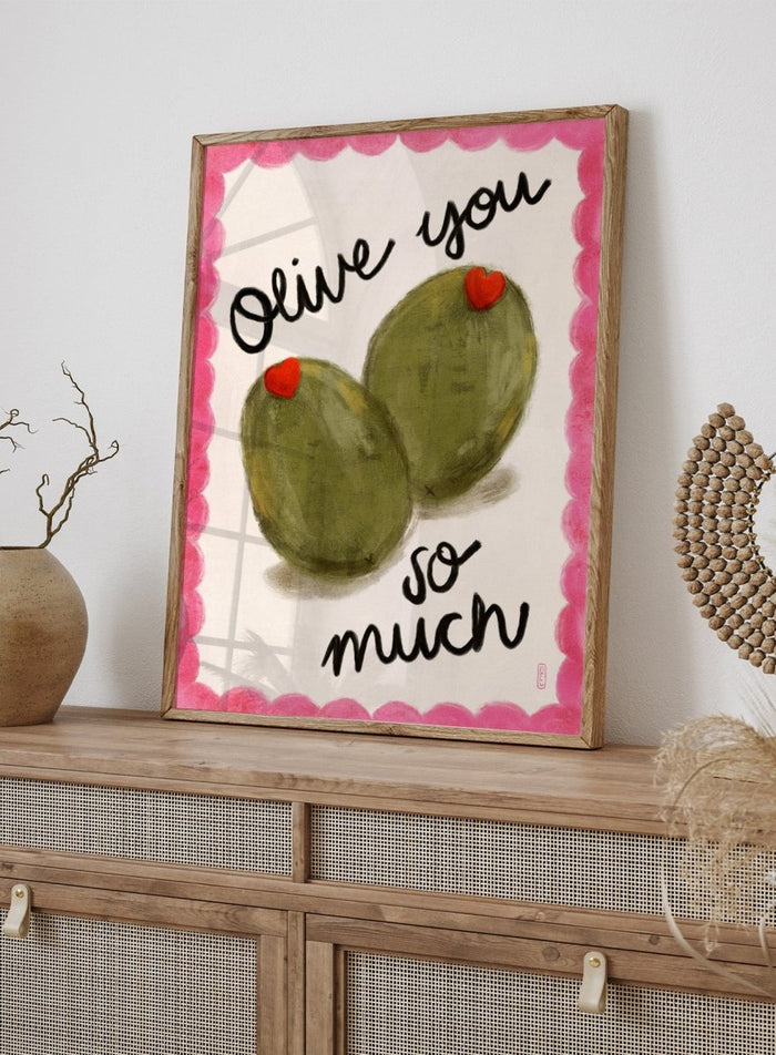 Two olives with red hearts and text 'Olive you so much' on a pink and white background. Olive You So Much by Dirkie Nell is a playful food art print featuring hand painted olives, pink accents, handwritten typography, and whimsical kitchen art details.