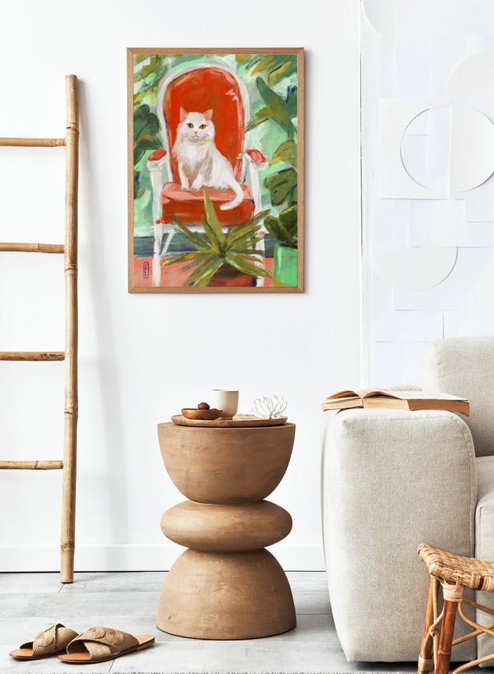 White cat on a red chair surrounded by green plants. White Cat Orange Chair by Dirkie Nell is a contemporary cat art print featuring expressive brushwork, colorful interiors, lush green plants, and modern animal wall art.