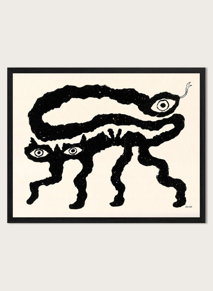 Framed artwork of a black and white creature with cat-like features and snake-like body. I Am Animals by Eden Kalif is a modern minimalist line art print featuring abstract animal forms in a bold black and white contemporary wall poster design.