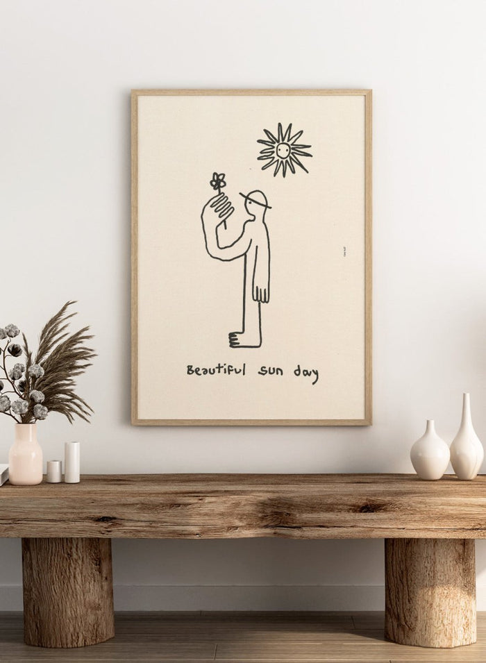 Black line drawing of a person with a flower and a sun, with 'Beautiful sun day' text on a beige background. Untitled by Eden Kalif is a modern line art print of a figure holding a flower under the sun, a contemporary minimalist wall poster with simple expressive drawing.