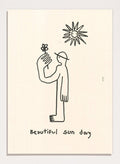 Black line drawing of a person with a flower and a sun, with 'Beautiful sun day' text on a beige background. Untitled by Eden Kalif is a modern line art print of a figure holding a flower under the sun, a contemporary minimalist wall poster with simple expressive drawing.