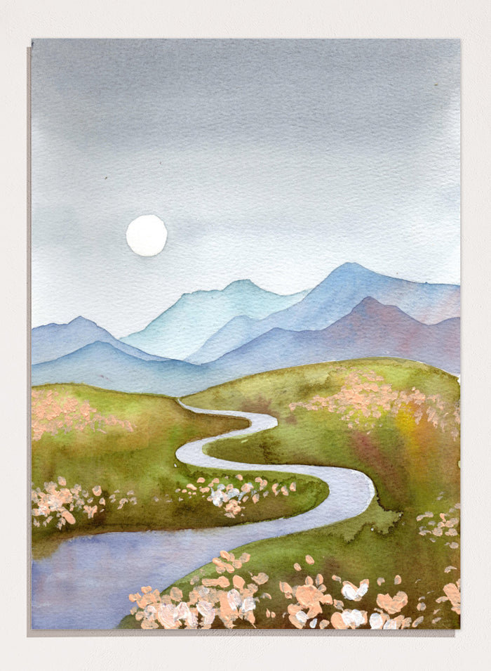 Watercolor landscape painting of a winding river flowing through green hills with pink flowers, blue mountains in the background, and a white sun in a gray sky. Shop Serene Mountain Path by Ekaterina Prisich, a landscape art print featuring a winding valley path, blue mountains, soft flowers, and a white moon.