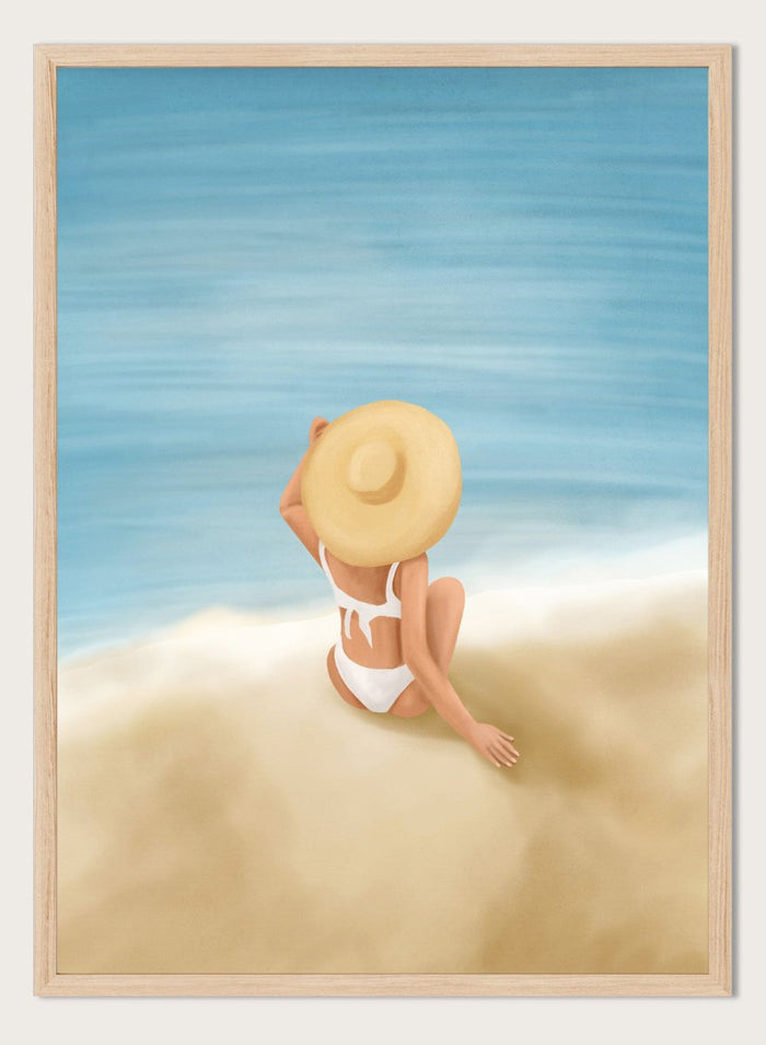 Woman in a white bikini and sun hat sitting on sand looking at ocean. Ocean View Relaxation by Flow Line is a coastal wall art print featuring a woman by the ocean, soft blue tones, beach decor, and relaxed summer style.