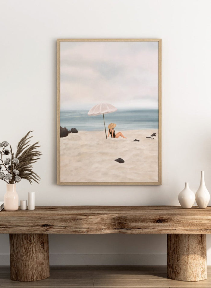 Woman under an umbrella on a beach with a calm ocean and sky. Serene Beach Scene by Flow Line is a coastal art print featuring a woman by the ocean, beach umbrella, seaside illustration, and summer wall art.