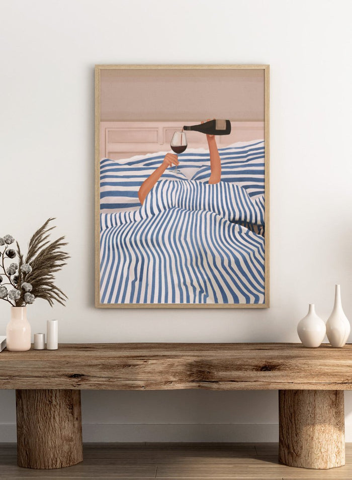 Person lying in bed pouring wine into a glass, wearing striped sheets. Wine In Bed by Flow Line is a playful art print featuring striped bedding, red wine, minimalist illustration, and cozy bedroom decor.