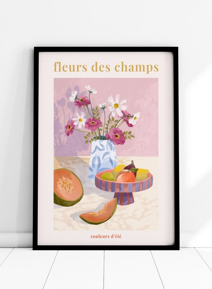 Illustration of a vase with flowers and fruits on a table against a pink background, with text 'fleurs des champs' and 'couleurs d'ete'. Fleur Des Champs Pink by Goed Blauw is a colorful still life art print and wall poster featuring flowers, fruit, and a patterned vase in a modern composition.