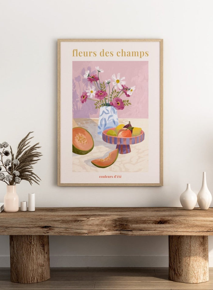 Illustration of a vase with flowers and fruits on a table against a pink background, with text 'fleurs des champs' and 'couleurs d'ete'. Fleur Des Champs Pink by Goed Blauw is a colorful still life art print and wall poster featuring flowers, fruit, and a patterned vase in a modern composition.