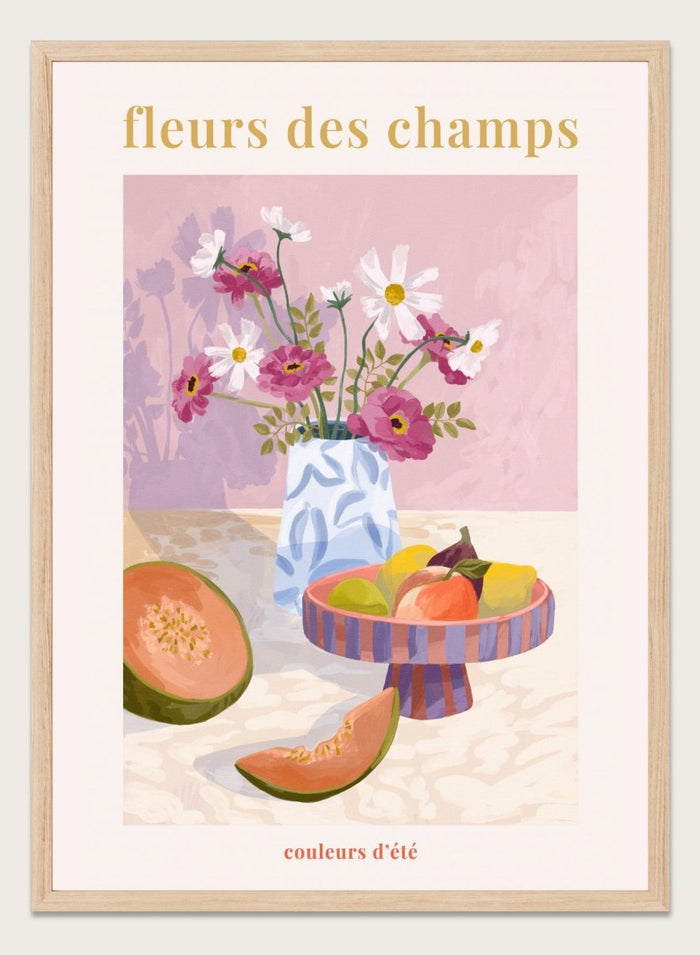 Illustration of a vase with flowers and fruits on a table against a pink background, with text 'fleurs des champs' and 'couleurs d'ete'. Fleur Des Champs Pink by Goed Blauw is a colorful still life art print and wall poster featuring flowers, fruit, and a patterned vase in a modern composition.