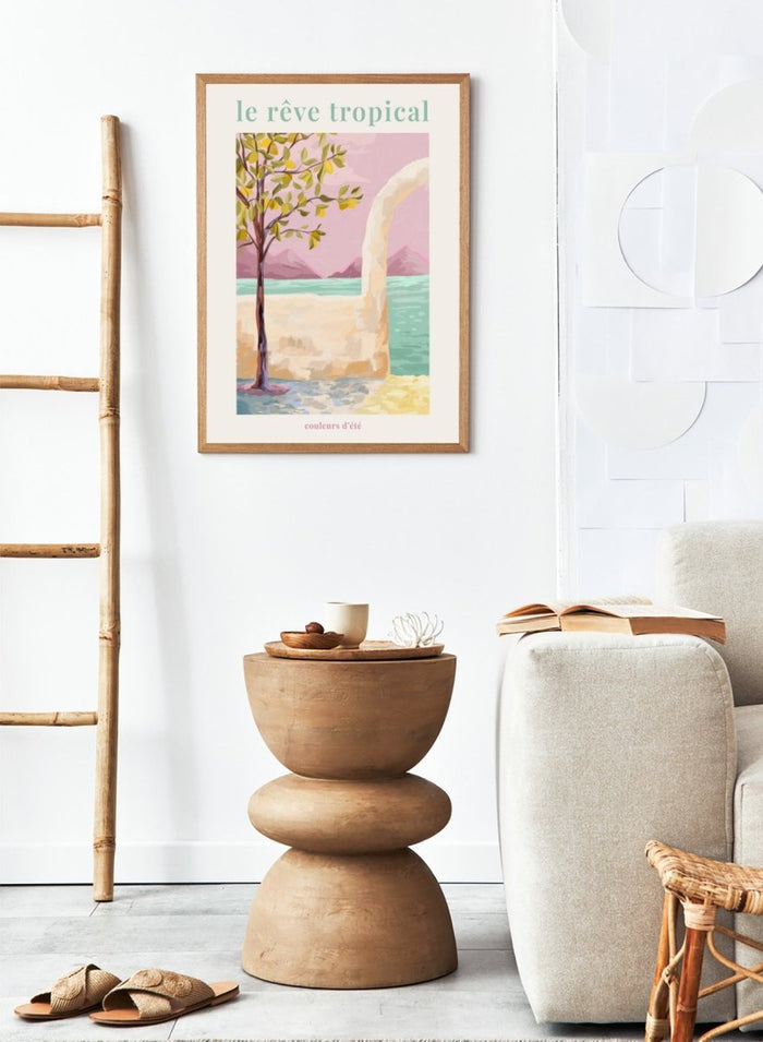 Artistic depiction of a tropical scene with a tree, beach, and mountains, featuring the text 'le rève tropical' and 'couleurs d'été'. Le Rêve Tropical Lemon Tree by Goed Blauw is a coastal art print and wall poster featuring a lemon tree, archway, and ocean view in warm pastel tones.