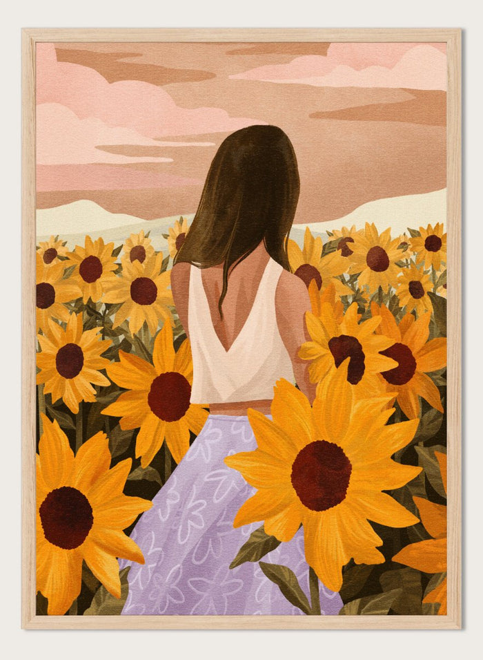 Woman in a white top and purple pants sitting among sunflowers with a scenic background. Sunflower Evenings by Goed Blauw is a fine art print and wall poster featuring a woman standing in a sunflower field with warm golden tones.