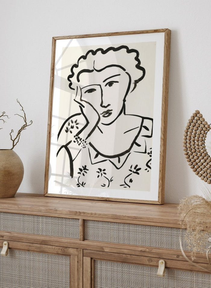 Black line art of a woman with floral patterns on a white background. Jeune Fille Accoudée by Henri Matisse is a minimalist portrait art print featuring expressive black linework, floral detailing, and refined French modernist design.