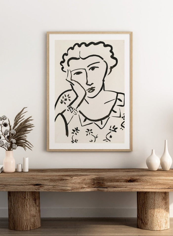 Black line art of a woman with floral patterns on a white background. Jeune Fille Accoudée by Henri Matisse is a minimalist portrait art print featuring expressive black linework, floral detailing, and refined French modernist design.
