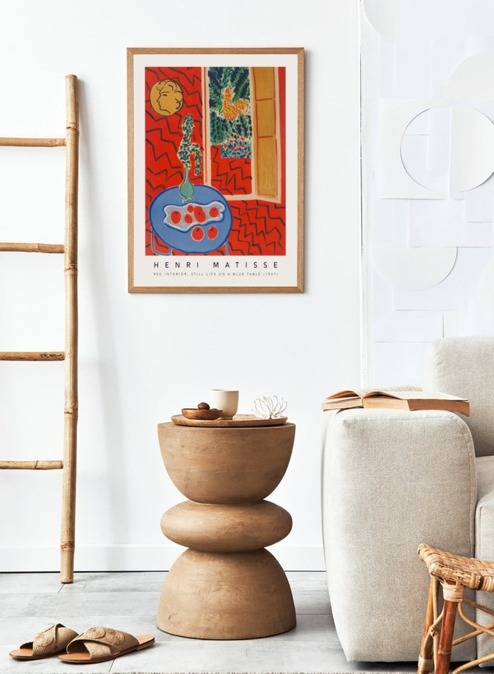 Artistic depiction of a still life scene with a blue table, vase, and fruit, by Henri Matisse. Red Interior, Still Life on a Blue Table by Henri Matisse is a 1947 modern art print featuring bold color, expressive interiors, floral still life details, and iconic French design.